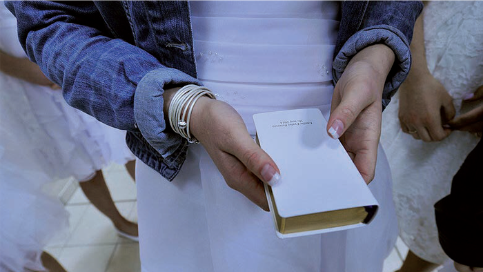 En person holder en lille hvid bog i hænderne.