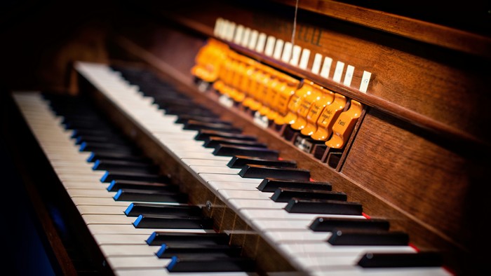 Et orgel med sorte og hvide tangenter og en række knapper.