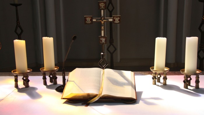 Ein Altar mit Kreuz, Kerzen und aufgeschlagenem Buch