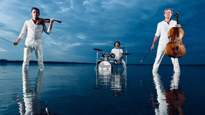 Drei Musiker spielen auf dem Wasser Geige, Cello und Schlagzeug