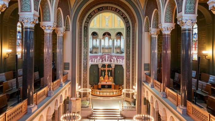 Indre del af en stor og præget kirke med høje buegange og lysende lys.