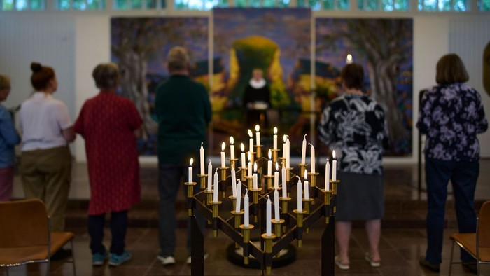 En gruppe af personer står i en kirke og ser på et maleri.