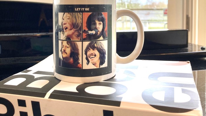 En tønde med billeder af Beatles medlemmer står på et Bibelen-bog.