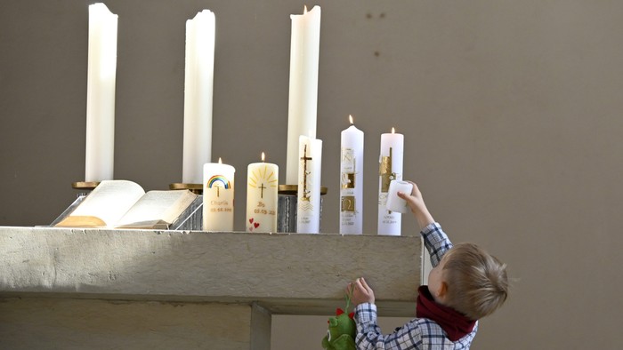 Kind zündet Kerze in Kirche an
