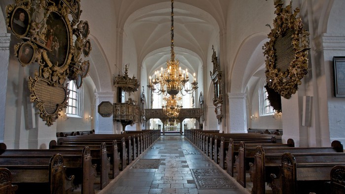 Indre del af kirke med høje vægge og belysning fra kandle.