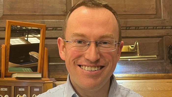 Man wearing glasses and blue shirt smiling