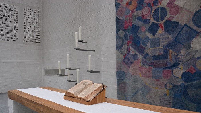 Ein weißer Raum mit einem Holzbalken, Kerzen und einem Buch