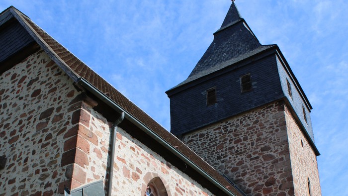 Steinerne Kirche mit hohem Turm und blauem Himmel.