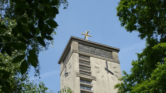 Der Turm einer Kirche ragt zwischen Bäumen empor