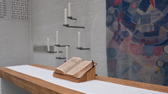 Ein weißer Raum mit einem Holzbalken, Kerzen und einem Buch