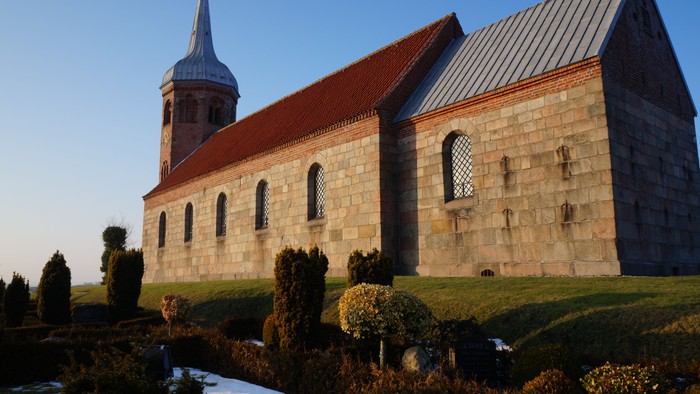 En gammel kirke med spire og røde tagtag.