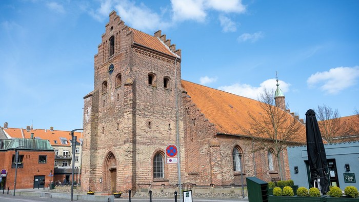 Gamle kirke med teglmur og spistegning i bymiljø