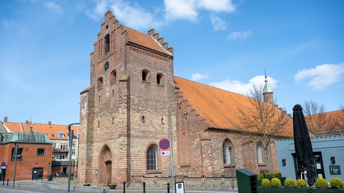 Gamle kirke med teglmur og spistegning i bymiljø