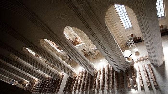 Indre del af en stor kirke med høje buer og lysende vinduer