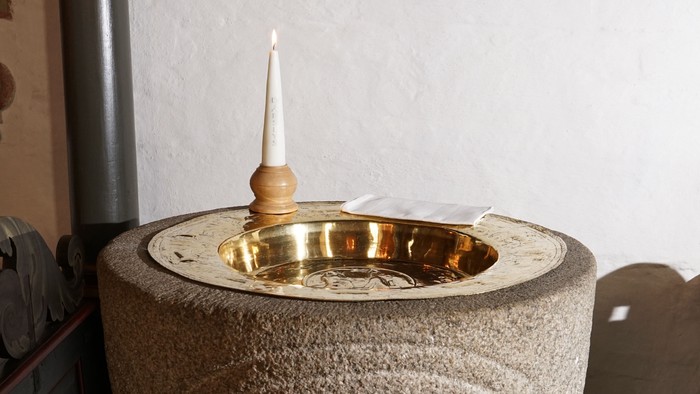 En stenfontæne med en lille lysestage på toppen.