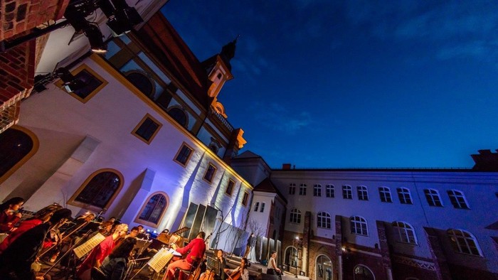 Abendliche Stadtansicht mit beleuchteten Gebäuden und Menschen auf der Straße