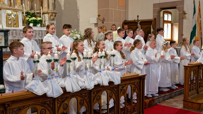 Kinder in weißen Kleidern beten in einer Kirche