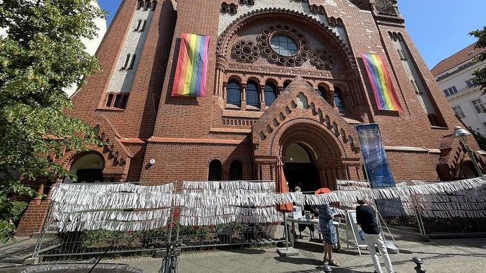 Großes Backsteingebäude mit zwei Fahnen und Menschen davor