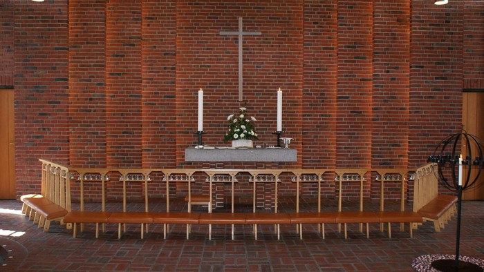 Kirkens interiør med alter, lysestake og træbænke.