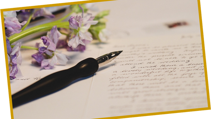 En blæk og violette blomster på papir med håndskrevet brev