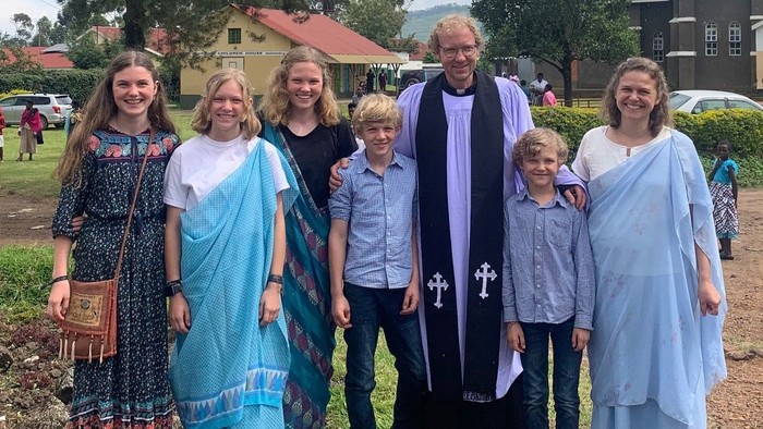 Eine Gruppe von Menschen posiert mit einem Pfarrer im Freien