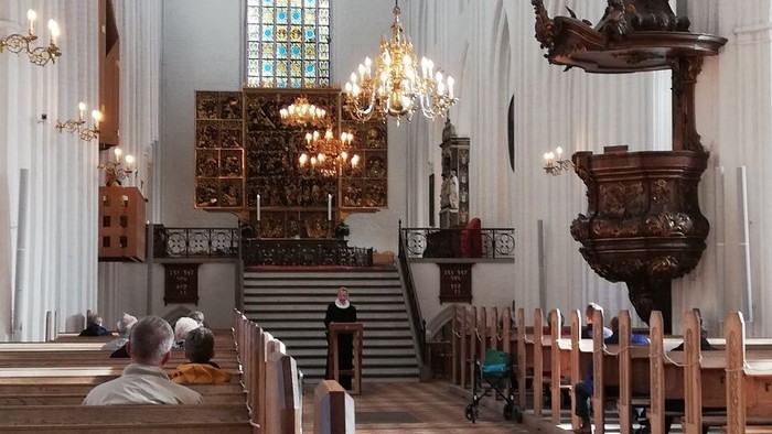 Indenrig af en stor kirke med høje vægge og bænke.