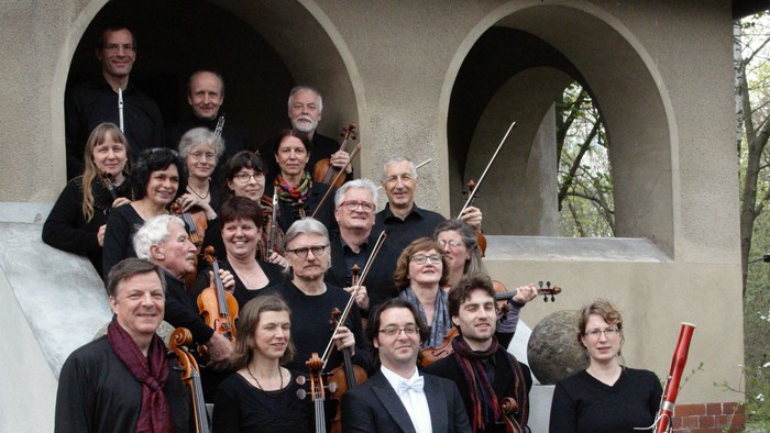 Ein Orchester posiert mit seinen Instrumenten vor einem Gebäude
