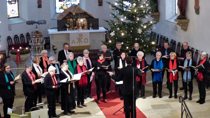 Ein Chor singt in einer Kirche vor einem Weihnachtsbaum