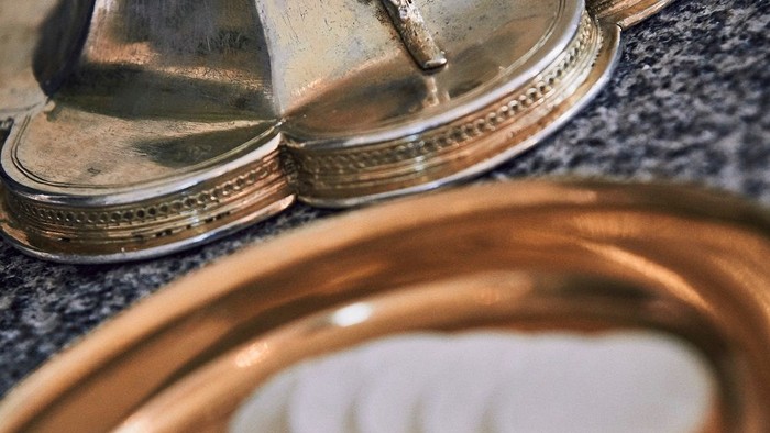 En messing skål med hostier og en messingskål med kors.