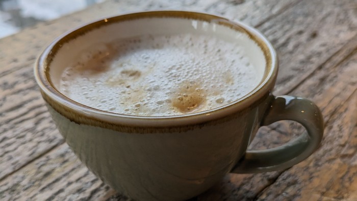 Eine Tasse Cappuccino auf einem Holztisch.