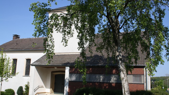 Ein zweistöckiges Haus mit einem Baum davor und einem klaren blauen Himmel.