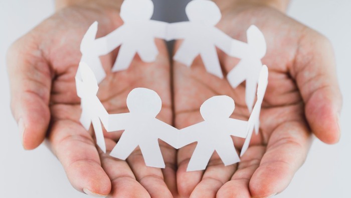 En person holder et papirkæmpemønster af en kreds af figurer.