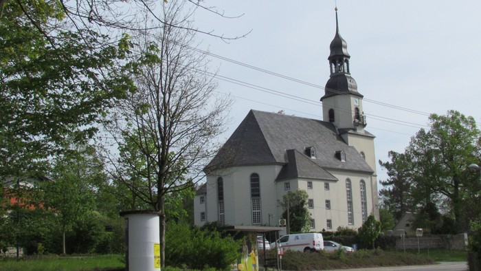 Kirchengelände mit weißem Kirchturm und umgebender Natur
