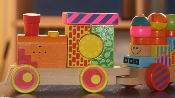 Buntes Holzspielzeug, darunter ein Zug und ein Stapel farbiger Blöcke