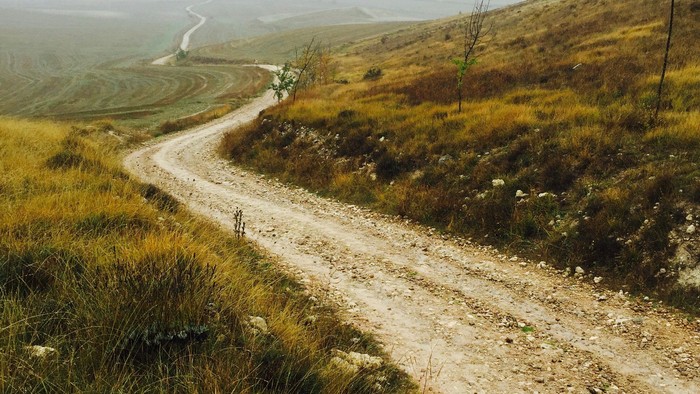 En støvende vej gennem en åben landskab.