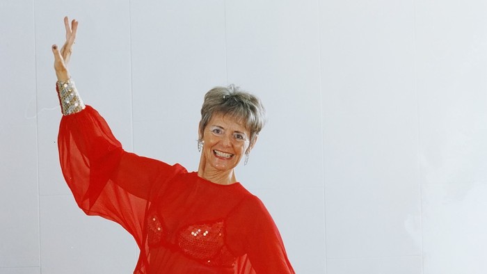 En glad kvinde i rød kjole danser.