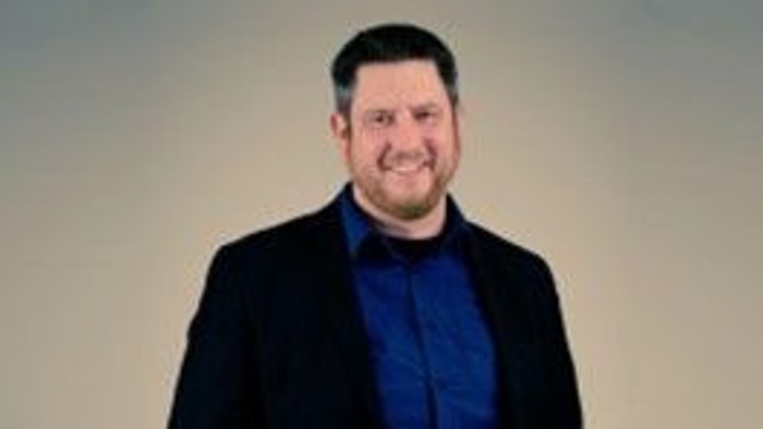 En mand i mørk suite og blå skjorte.