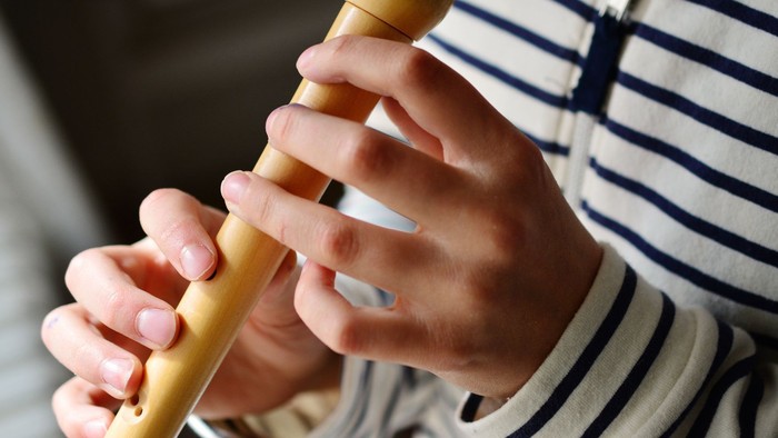 Eine Person, die eine gelbe Blockflöte spielt.