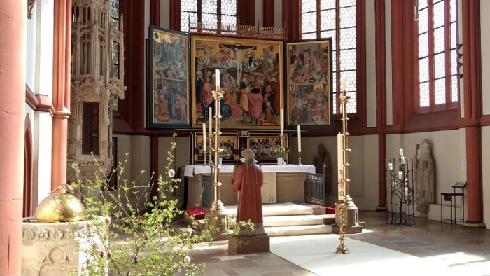 Der Altarraum der Kilianskirche mit dem Altar, Taufbecken und einem Osterstrauß im Vordergrund.