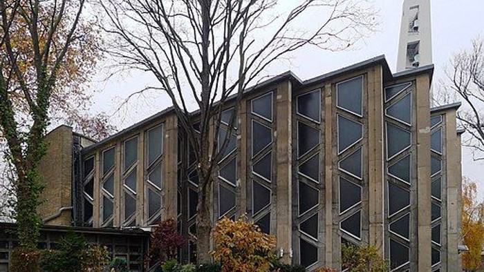 Moderne Kirche mit großen Fenstern und Bäumen im Herbstlaub