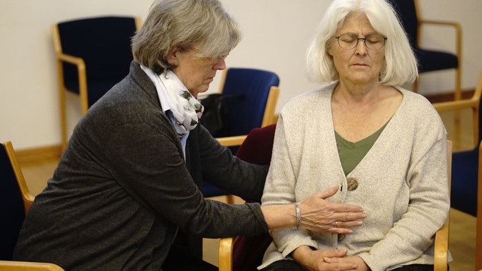 Zwei ältere Frauen sitzen in einem Raum mit Stühlen und unterhalten sich.