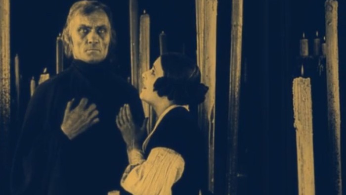 Ein Mann greift nach einer Frau in einem dunklen Raum.