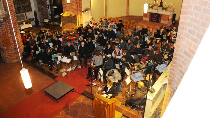 Große Menschenmenge in Kirche, viele sitzen, einige stehen, viele Kerzen, christliche Symbole