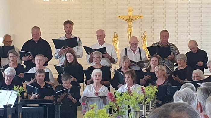 En kirkekor med flere sangere og musikere under ledelse af en præst.