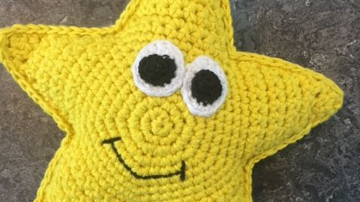 En gul crochet stjerne med øjne og mund på en granitflise