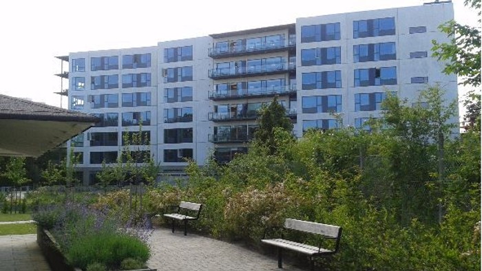 En moderne bygning med mange vinduer og en træstue med bænke.