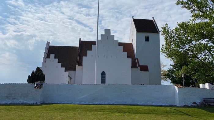 Et hvidt og sort tårn med græsplæne og træer.