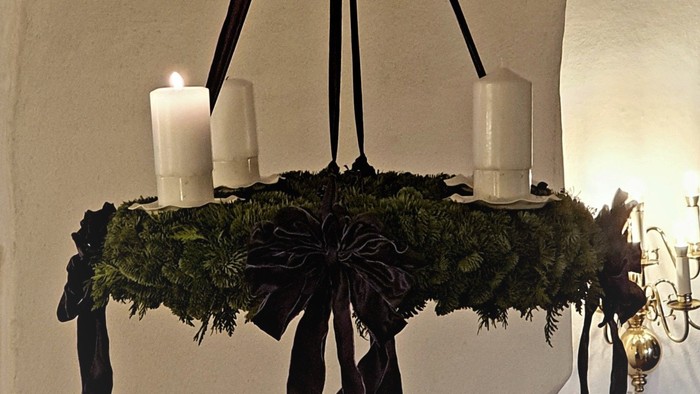 En kranse med lys og blomster hænger fra takken