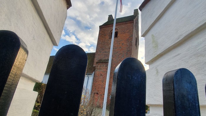 En rød murstenstårn med flag og bueformede vinduer.
