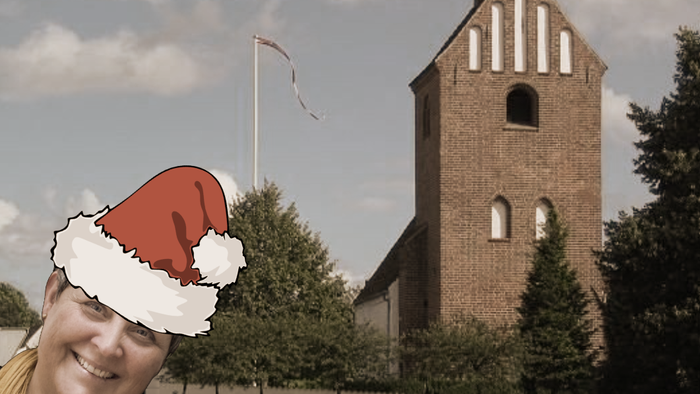 En kvinde med julehat foran kirke.